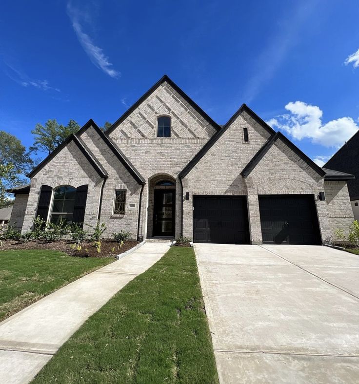 Completed brick residence with steep gables, arched entry, and new landscaping