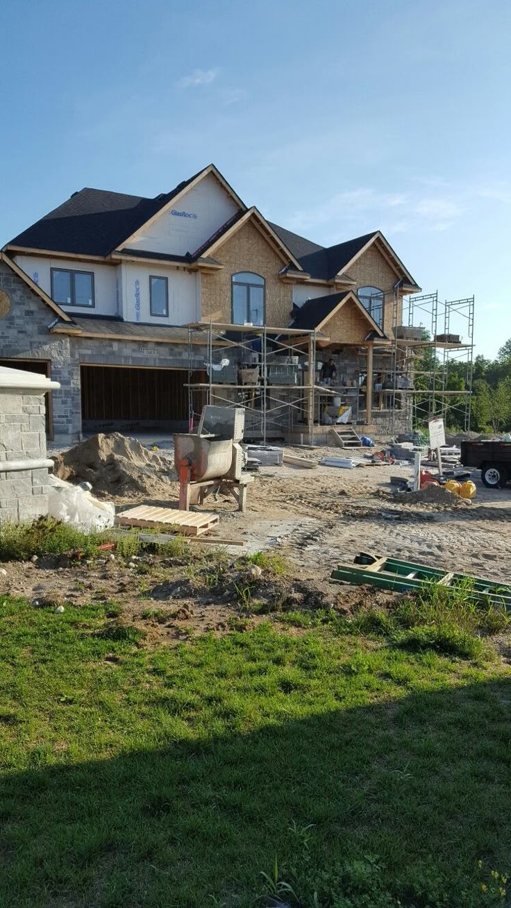 Home addition under construction with scaffolding, stone veneer, and framing in place