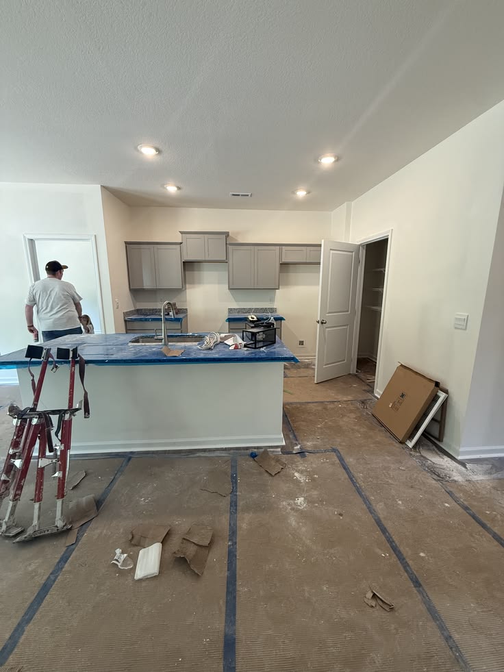 Kitchen under construction with cabinetry set and countertops protected during finish work